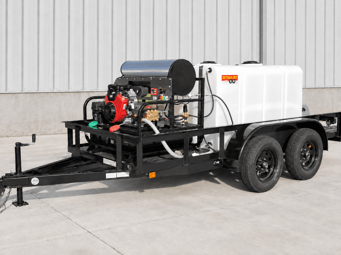 Close-up of a black DBP Series trailer bed showing a red Honda engine, pump, stainless hot-water coil, and white tank