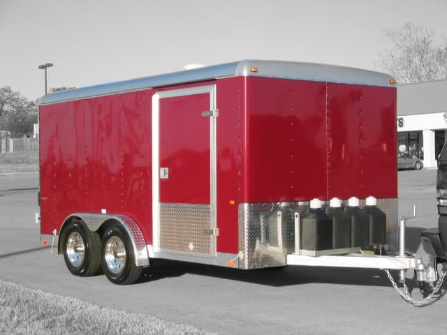 Red enclosed cargo trailer for the Tri-Brid system, with blue chemical jugs mounted near the rear bumper