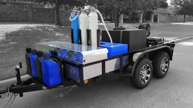 Touchless spot-free trailer with three cylindrical deionization tanks, a blue chemical tote, and jerry cans on a toolbox